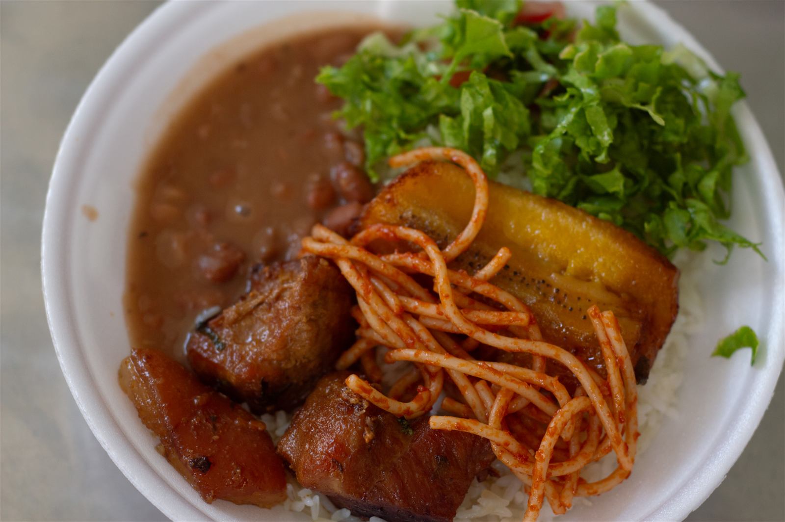 Prato com carne, banana frita, macarrão, feijão e salada