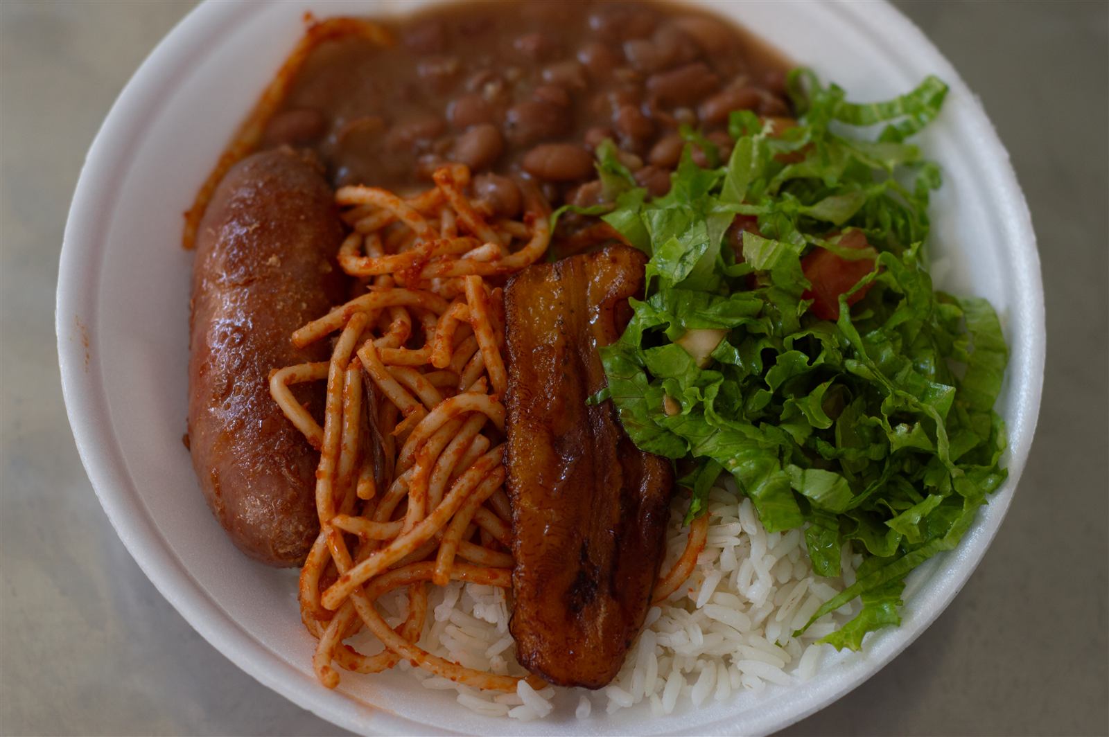 Prato farto: linguiça, macarrão, banana, feijão e salada